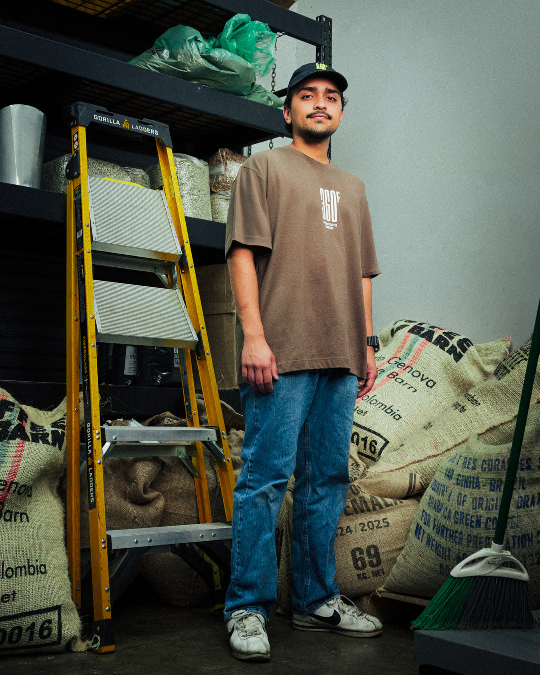 Man standing in a storage room with shelves and bags of coffee beans.