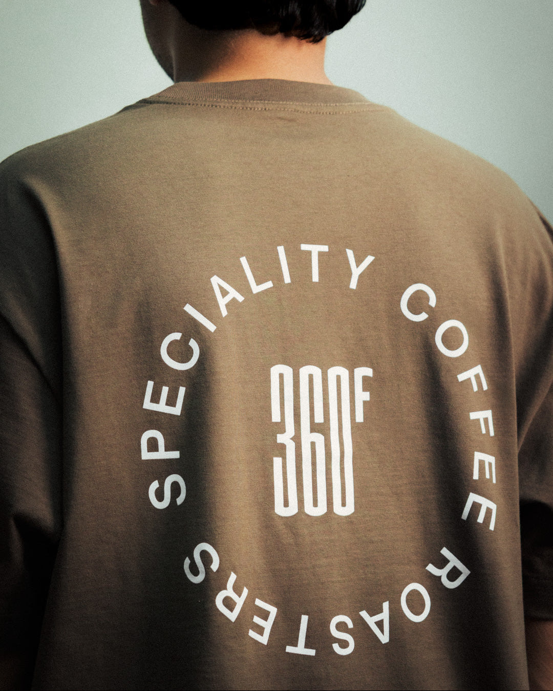 Person wearing a brown t-shirt with 'Specialty Coffee Roasters 360' logo on the back.
