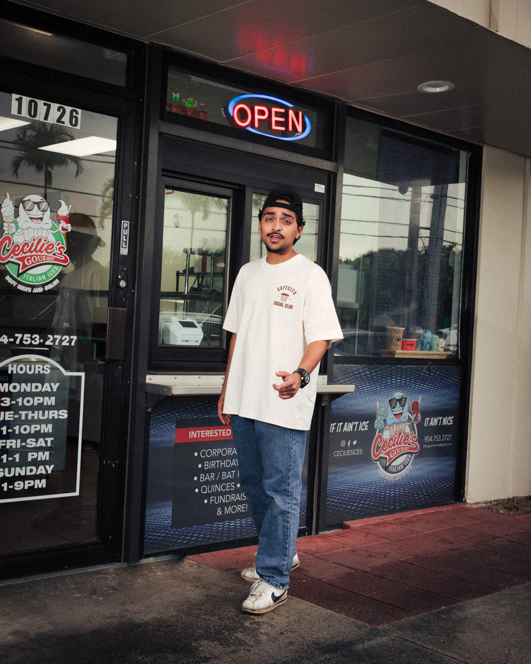 Man standing in front of a store entrance with a neon 'OPEN' sign